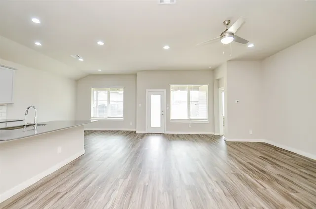a view of an empty room with a window and wooden floor