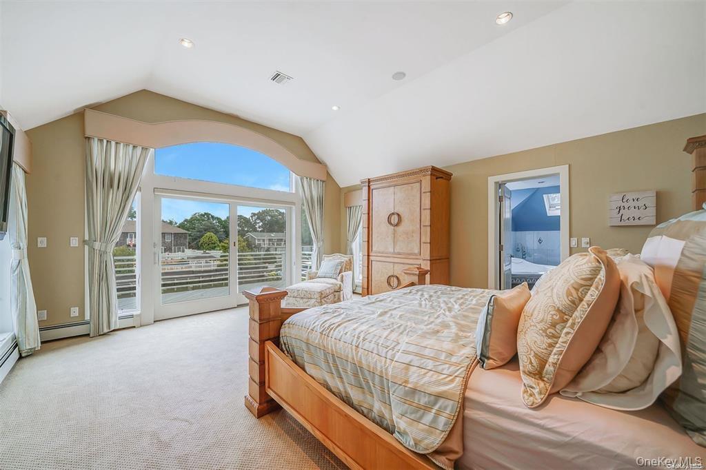 4 Mill Pond Road Hampton Bays, NY 11946 - Photo 14 of 24 a bedroom with a bed and a large window