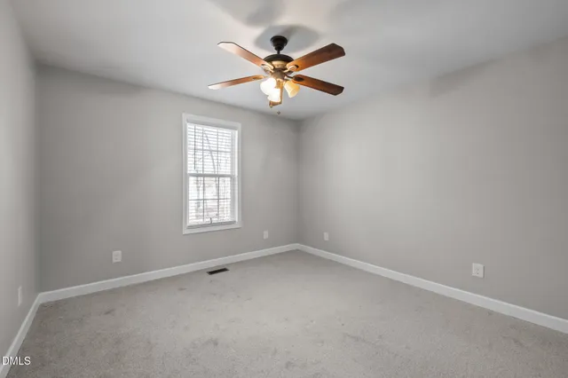 an empty room with window and ceiling fan