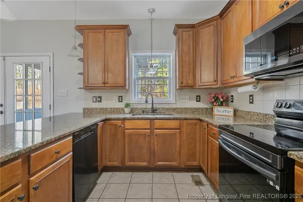 a kitchen with stainless steel appliances granite countertop a stove a sink and a microwave
