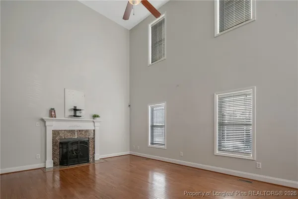 a view of an empty room with wooden floor fireplace and a window