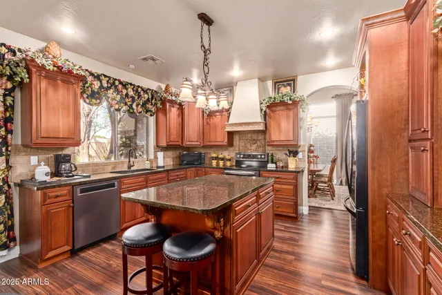 a kitchen with stainless steel appliances granite countertop a refrigerator a sink dishwasher a stove and white countertops with wooden floor