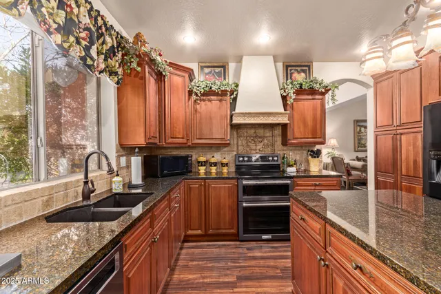 a kitchen with stainless steel appliances granite countertop a sink a stove top oven a counter space and cabinets