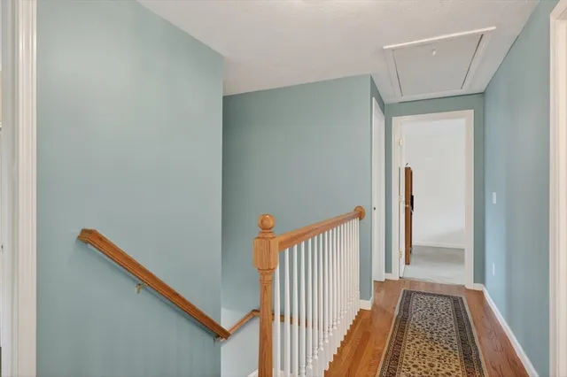 a view of a hallway with wooden floor and a bathroom