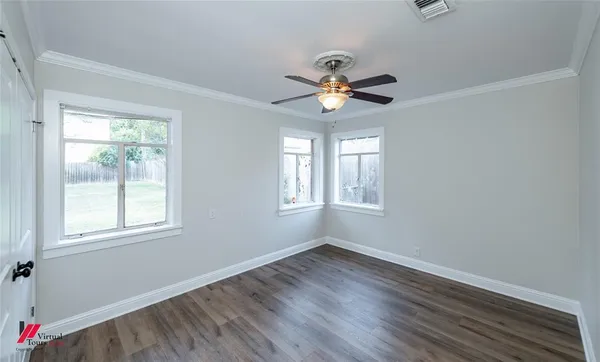 a view of an empty room with a window and wooden floor