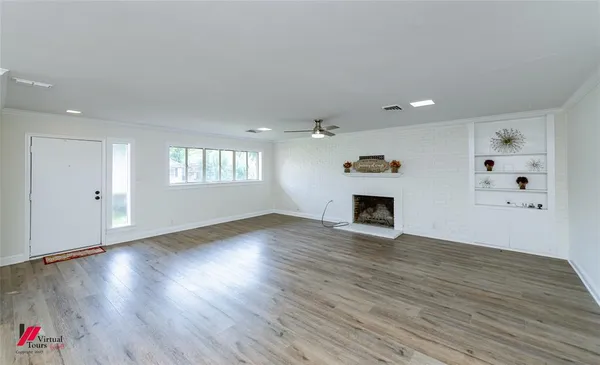 a view of an empty room with window and wooden floor