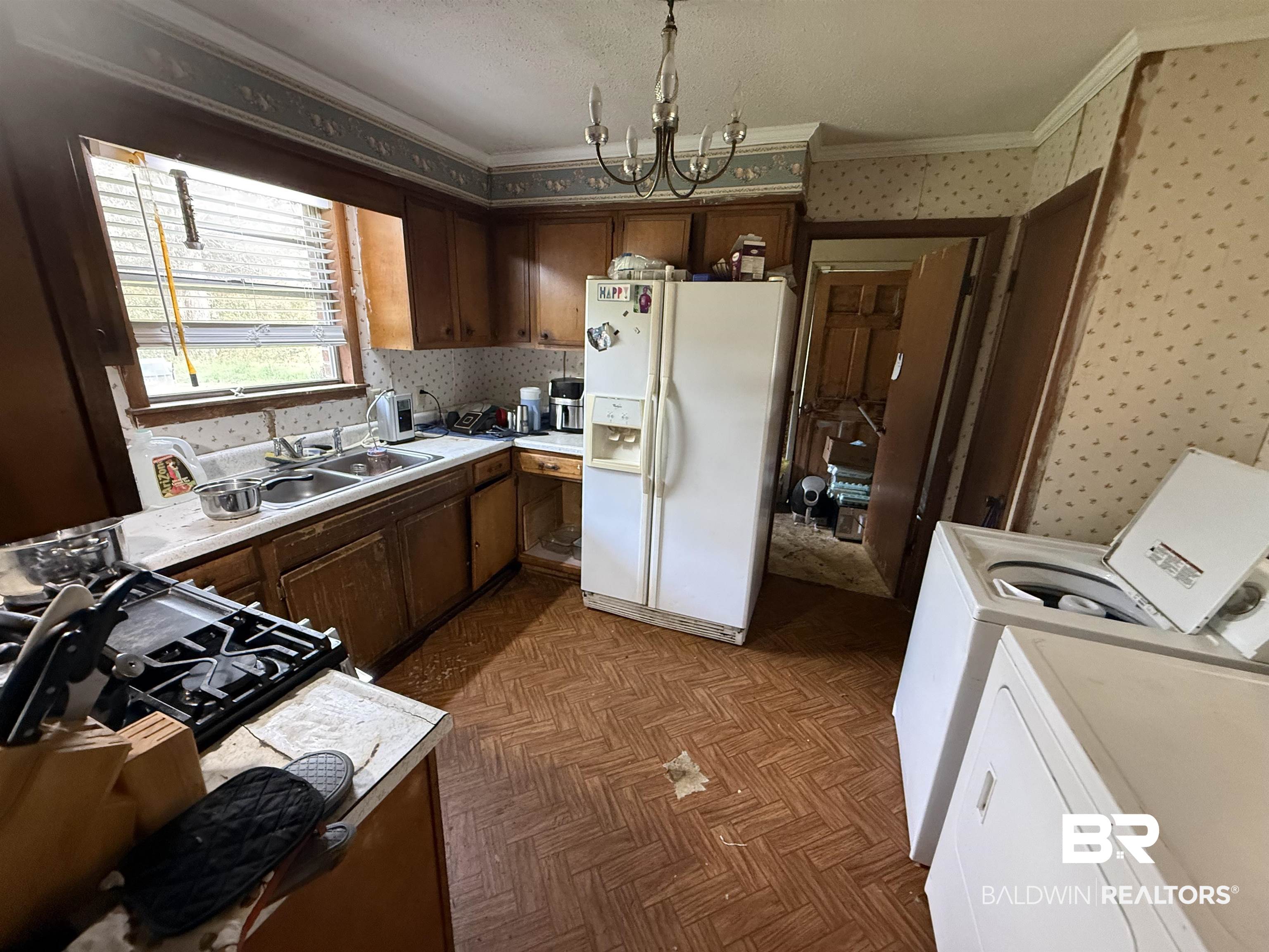 2807 Pea Ridge Road Brewton, AL 36426 - Photo 12 of 12 Kitchen featuring white refrigerator with ice dispenser, wallpapered walls, crown molding, light countertops, and a chandelier
