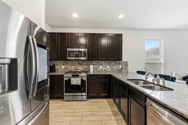a kitchen with stainless steel appliances granite countertop a sink stove and refrigerator