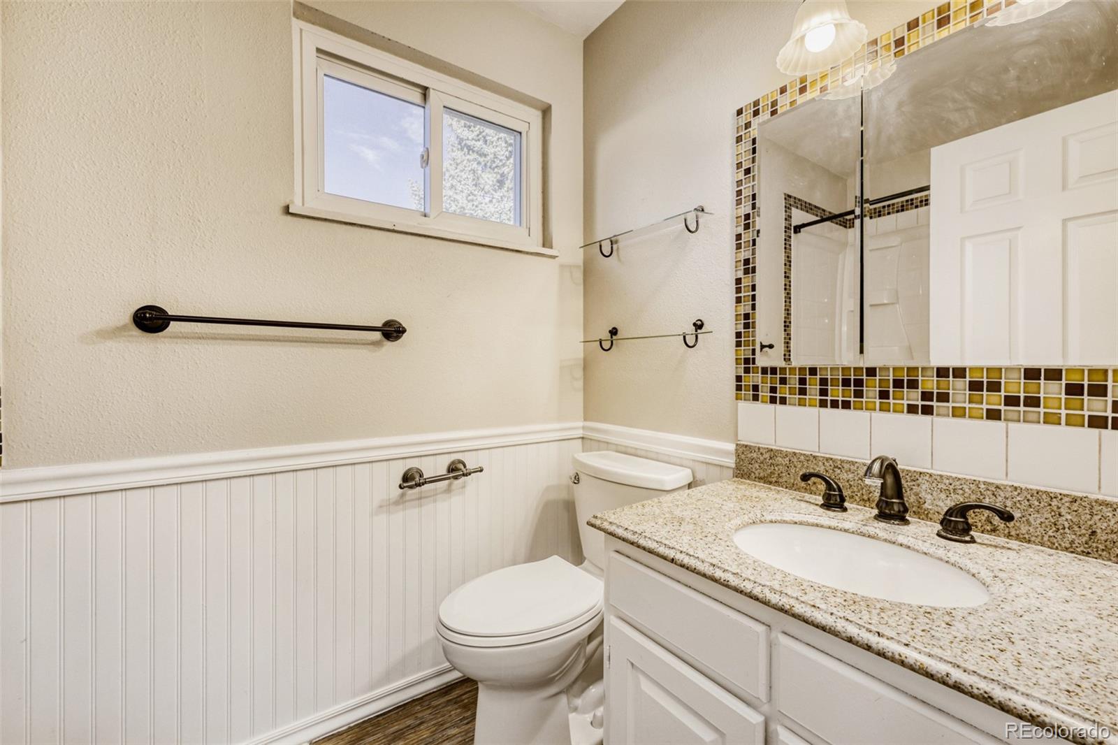9787 Lane Street Thornton, CO 80260 - Photo 15 of 29 a bathroom with a granite countertop sink mirror vanity and toilet