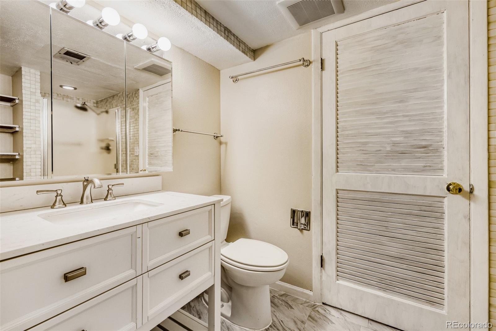 9787 Lane Street Thornton, CO 80260 - Photo 21 of 29 a bathroom with a granite countertop sink toilet a mirror a vanity and shower