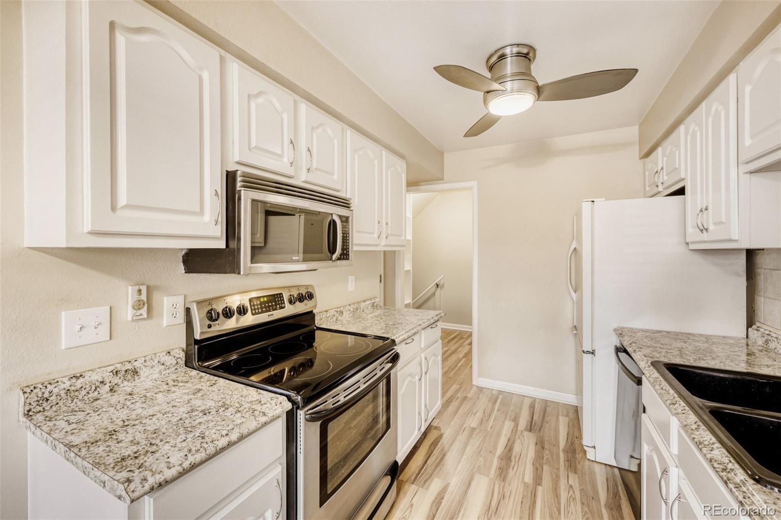 9787 Lane Street Thornton, CO 80260 - Photo 6 of 29 a kitchen with stainless steel appliances granite countertop a stove refrigerator and microwave