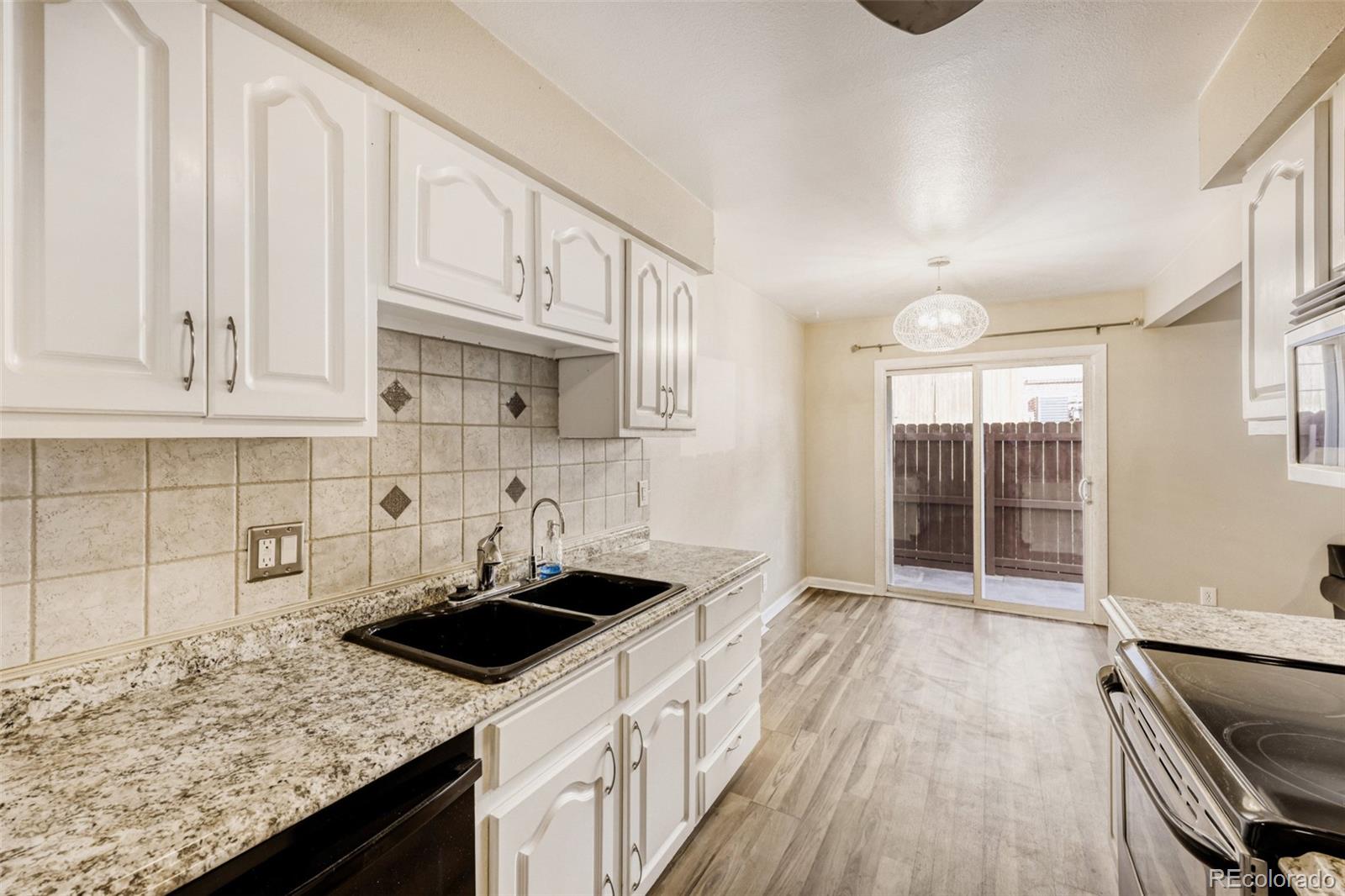 9787 Lane Street Thornton, CO 80260 - Photo 9 of 29 a kitchen with granite countertop a sink stove and cabinets