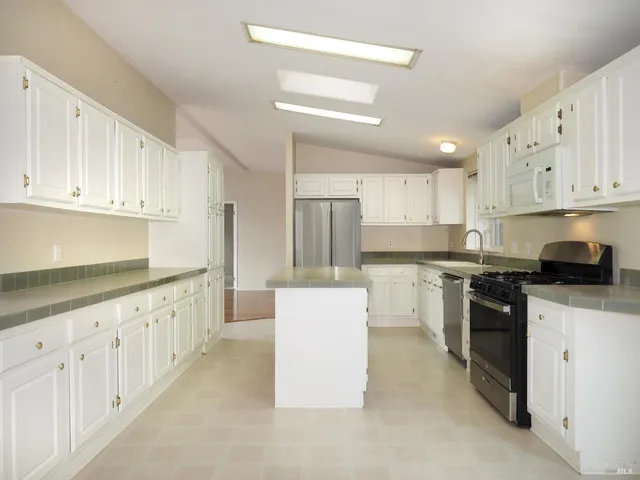 a kitchen with granite countertop white cabinets and stainless steel appliances