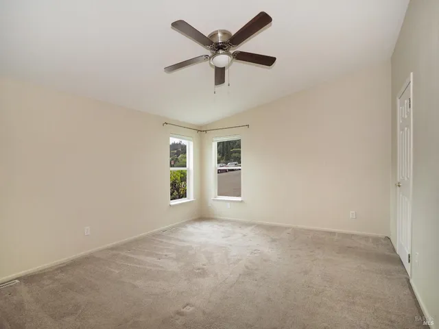 an empty room with windows and ceiling fan