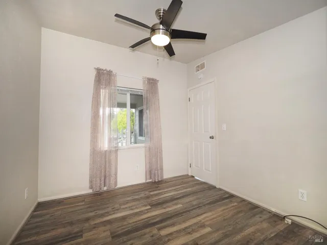 a view of an empty room with window and wooden floor
