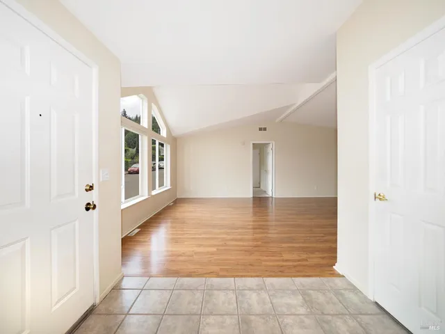 a view of a hallway with wooden floor and a bathroom