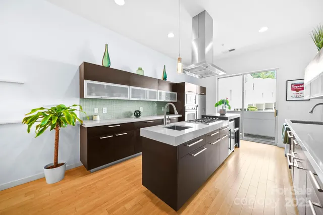 a kitchen with stainless steel appliances granite countertop a sink a stove and a wooden floors