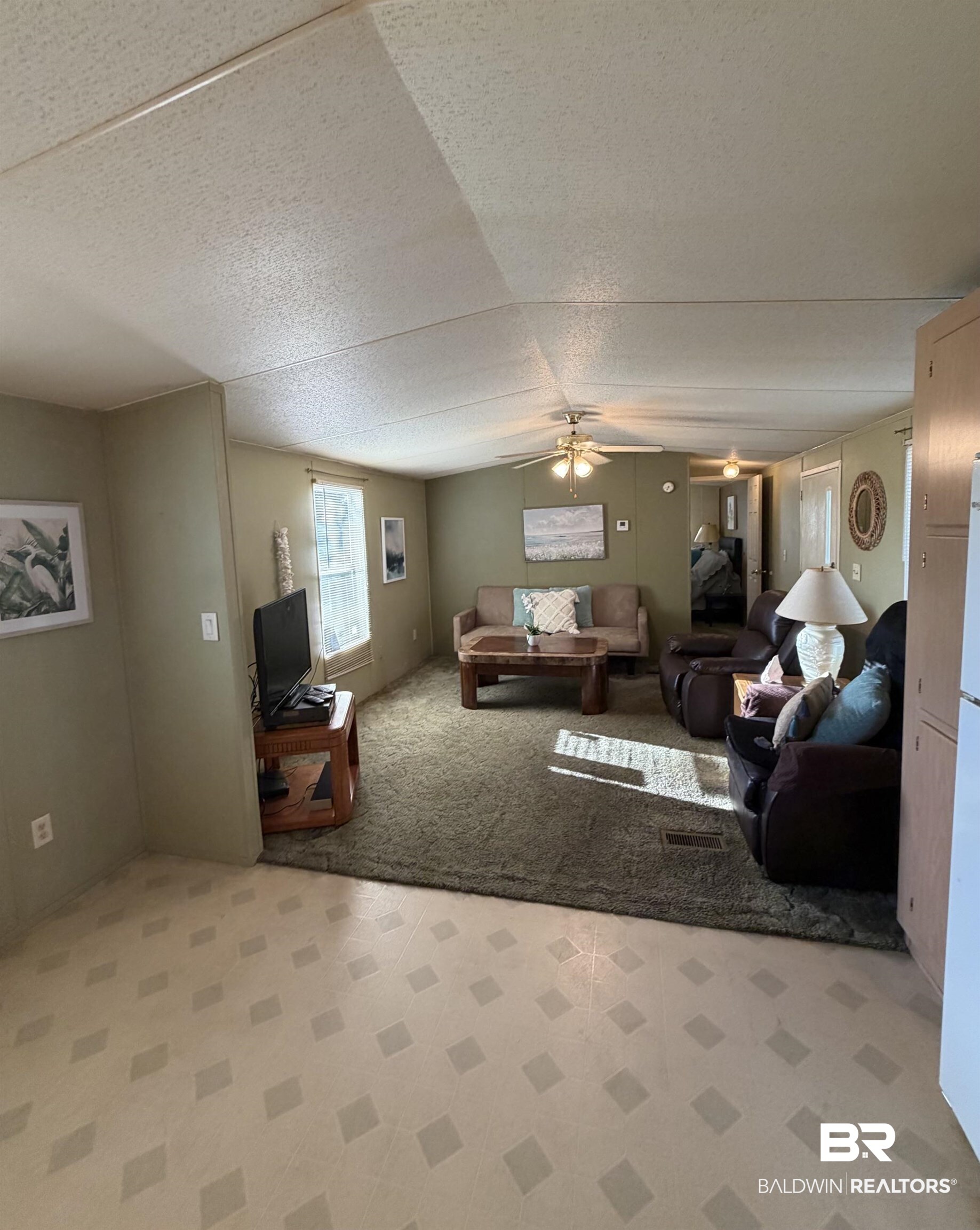 1125 Ridgewood Drive Lillian, AL 36549 - Photo 4 of 36 Spacious living area featuring a neutral color palette, ceiling fan, and mixed flooring with patterned vinyl and plush carpeting