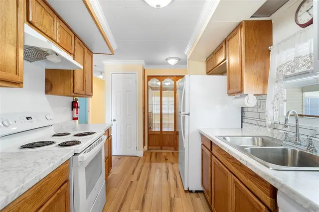 a kitchen that has a sink a stove and a wooden floors