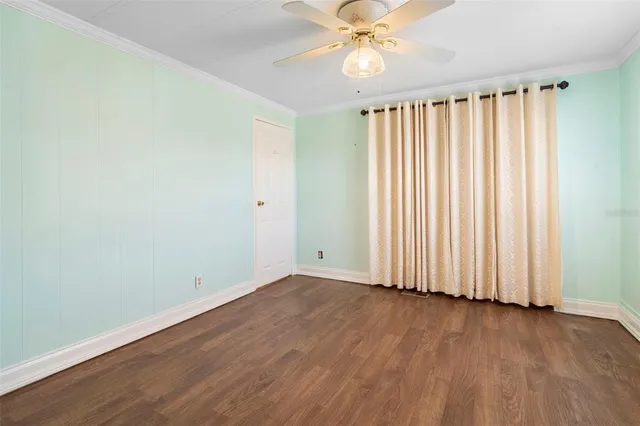 an empty room with wooden floor fan and windows
