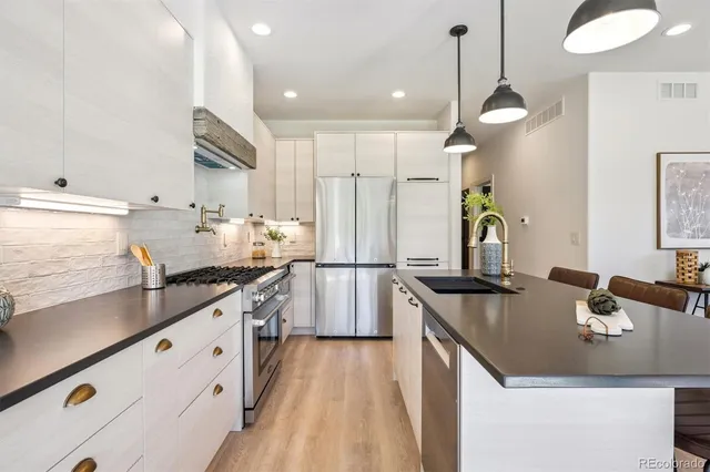 a kitchen with stainless steel appliances granite countertop a sink a stove and refrigerator