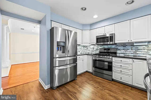 a kitchen with cabinets stainless steel appliances and wooden floor