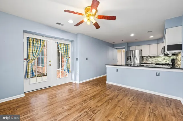 a view of kitchen with stainless steel appliances granite countertop a stove a sink dishwasher and a refrigerator with wooden floor