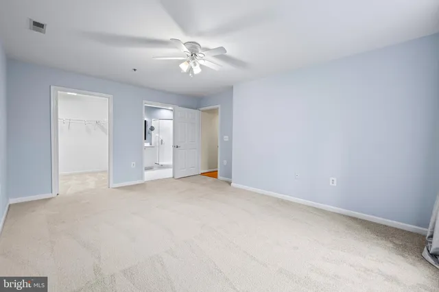 an empty room with chandelier fan and windows