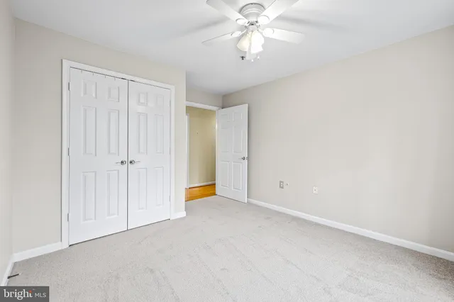 an empty room with a chandelier fan and windows