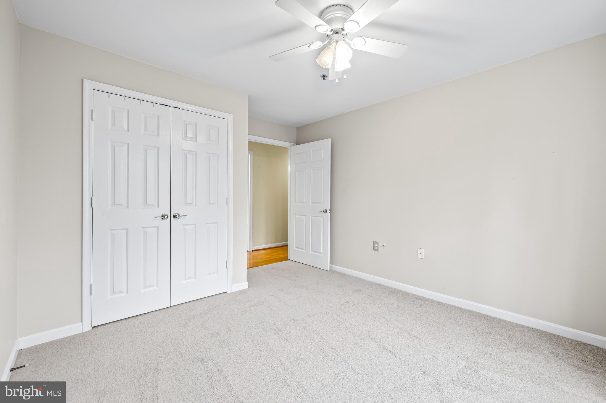 12011 Tralee Road, Unit 104 Lutherville-Timonium, MD 21093 - Photo 23 of 33 an empty room with a chandelier fan and windows