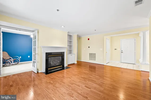 a view of an empty room with wooden floor and a fireplace