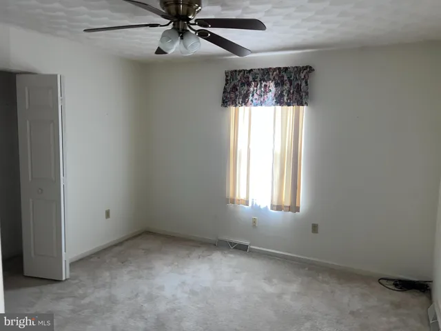 an empty room with a window and a fan