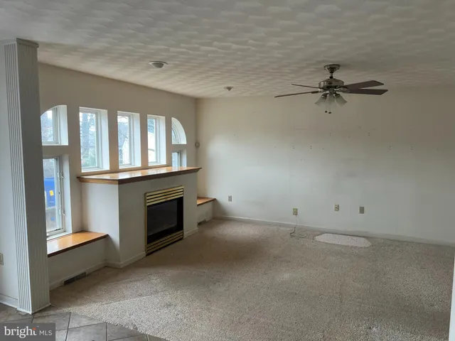 an empty room with windows and fireplace