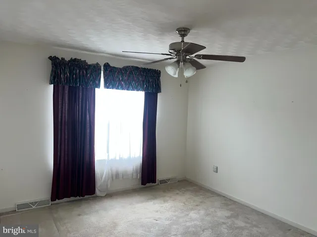 an empty room with windows and fan