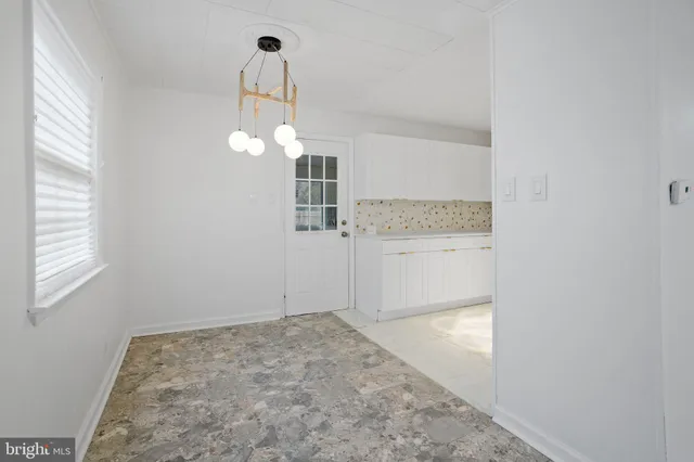 an empty room with a chandelier fan and windows