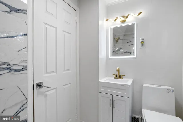 a bathroom with a toilet sink vanity and mirror