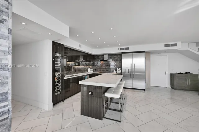 a kitchen with stainless steel appliances kitchen island granite countertop a refrigerator and a sink