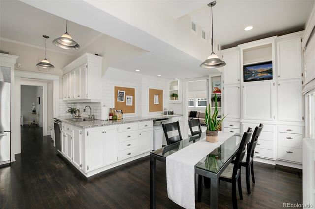 a kitchen with stainless steel appliances kitchen island granite countertop a table chairs and a refrigerator
