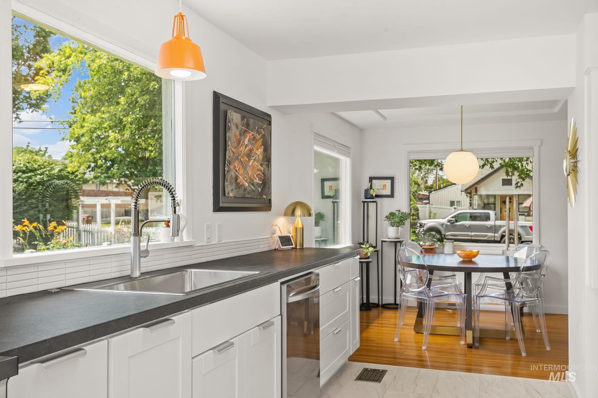 1315 8th Street Clarkston, WA 99403 - Photo 16 of 37 Kitchen featuring white cabinetry, dark countertops, a stainless steel sink with a gooseneck faucet, a white subway tile backsplash, and a large window overlooking exterior landscaping