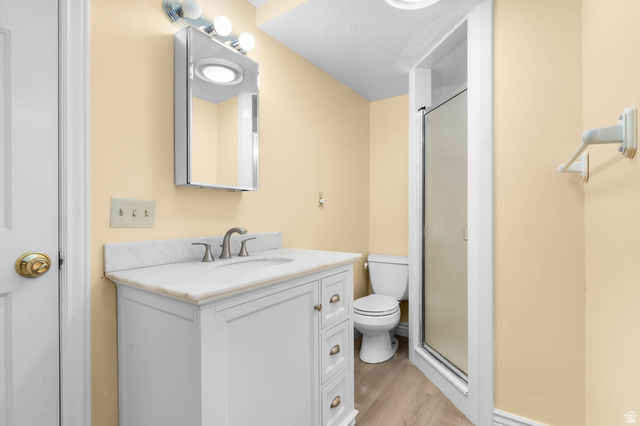 1822 East 9800th Street South Sandy, UT 84092 - Photo 35 of 38 Bathroom featuring vanity, a stall shower, light wood finished floors, and a textured ceiling