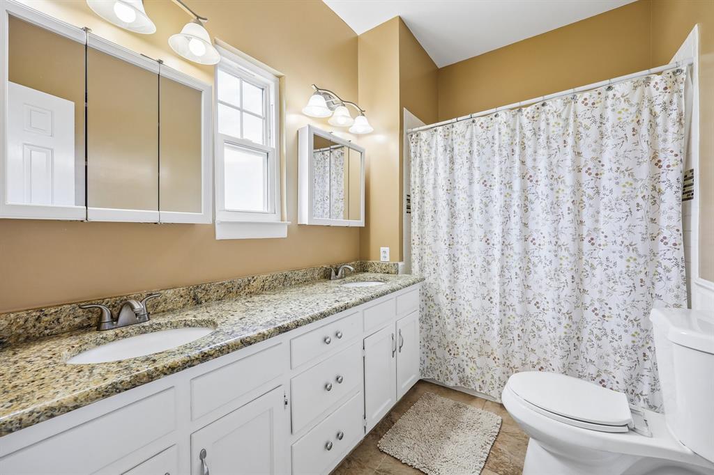 331 Radecke Road Krum, TX 76249 - Photo 34 of 40 Dual vanity with granite-finish countertop, undermount sinks, and brushed nickel fixtures