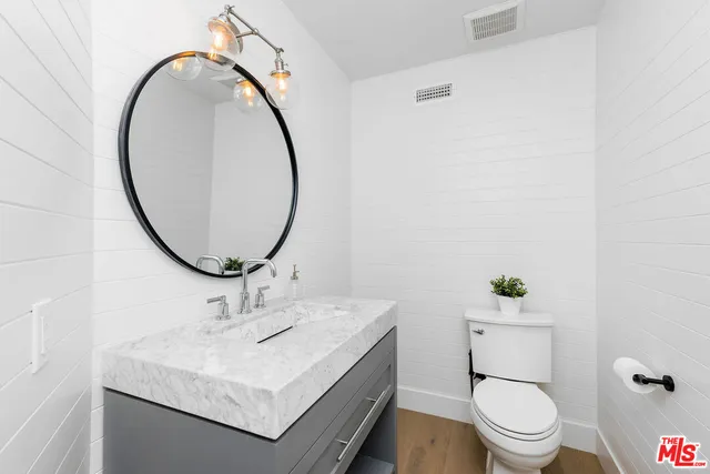 a bathroom with a granite countertop sink toilet and mirror