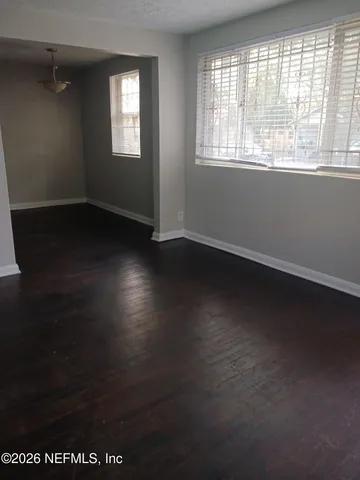 an empty room with wooden floor and windows