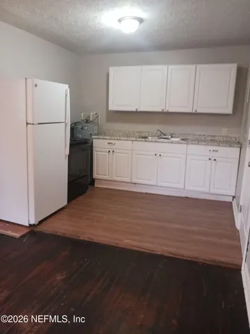 a kitchen with granite countertop white cabinets and refrigerator