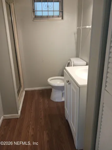 a bathroom with a toilet and a wooden floor