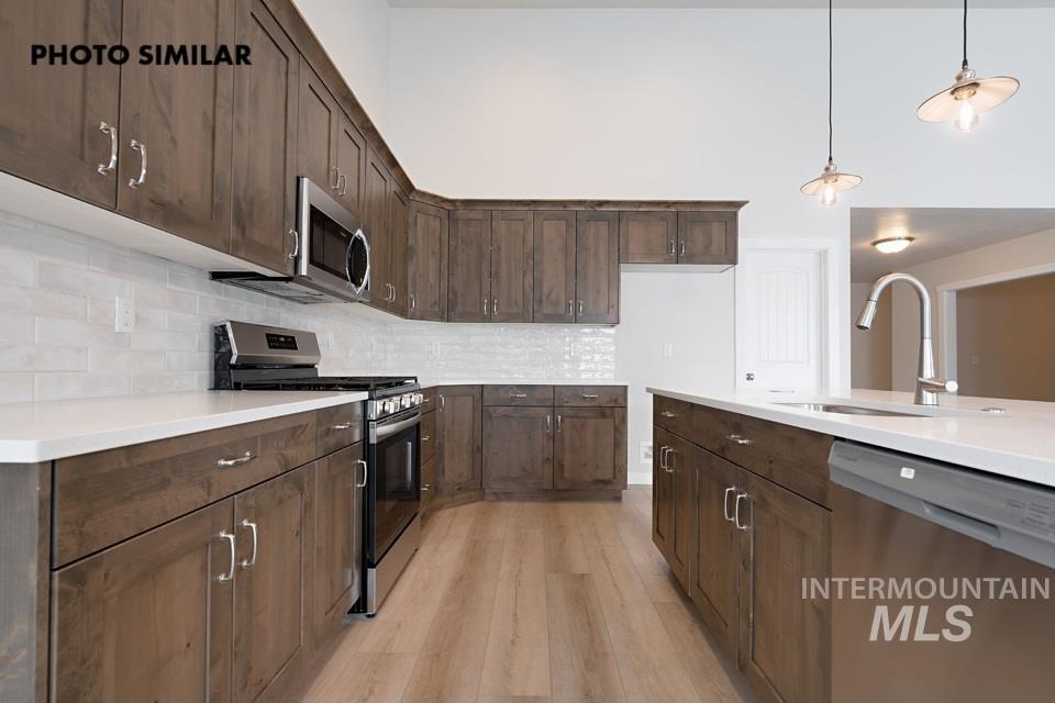 1645 Haystack Emmett, ID 83617 - Photo 10 of 33 Modern kitchen featuring dark wood-finish cabinetry, light countertops, and a white subway tile backsplash
