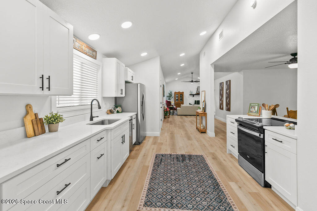 1815 Ford Road Mims, FL 32754 - Photo 13 of 59 a large white kitchen with stainless steel appliances granite countertop a lot of counter space and wooden floors