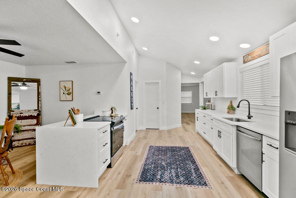 1815 Ford Road Mims, FL 32754 - Photo 16 of 59 a large white kitchen with a stove a sink a refrigerator and white cabinets