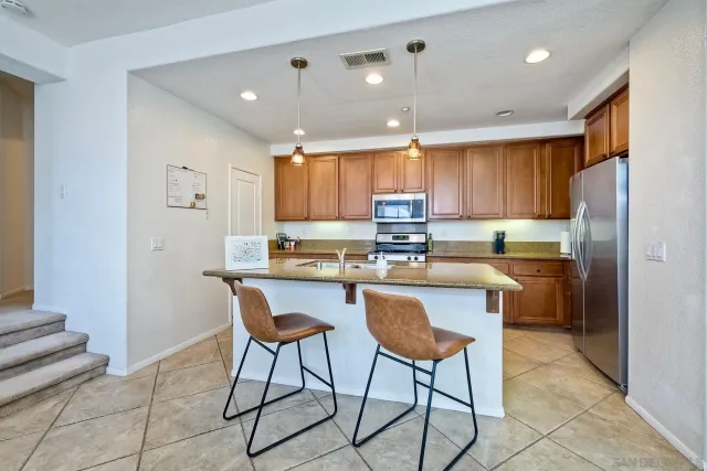 a kitchen with kitchen island granite countertop wooden cabinets and a refrigerator