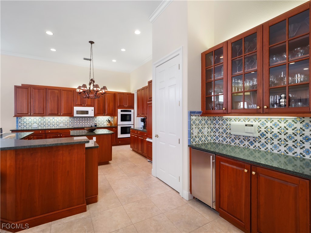 11511 Compass Point Drive Fort Myers, FL 33908 - Photo 14 of 46 a open kitchen with stainless steel appliances kitchen island granite countertop a refrigerator and wooden cabinets